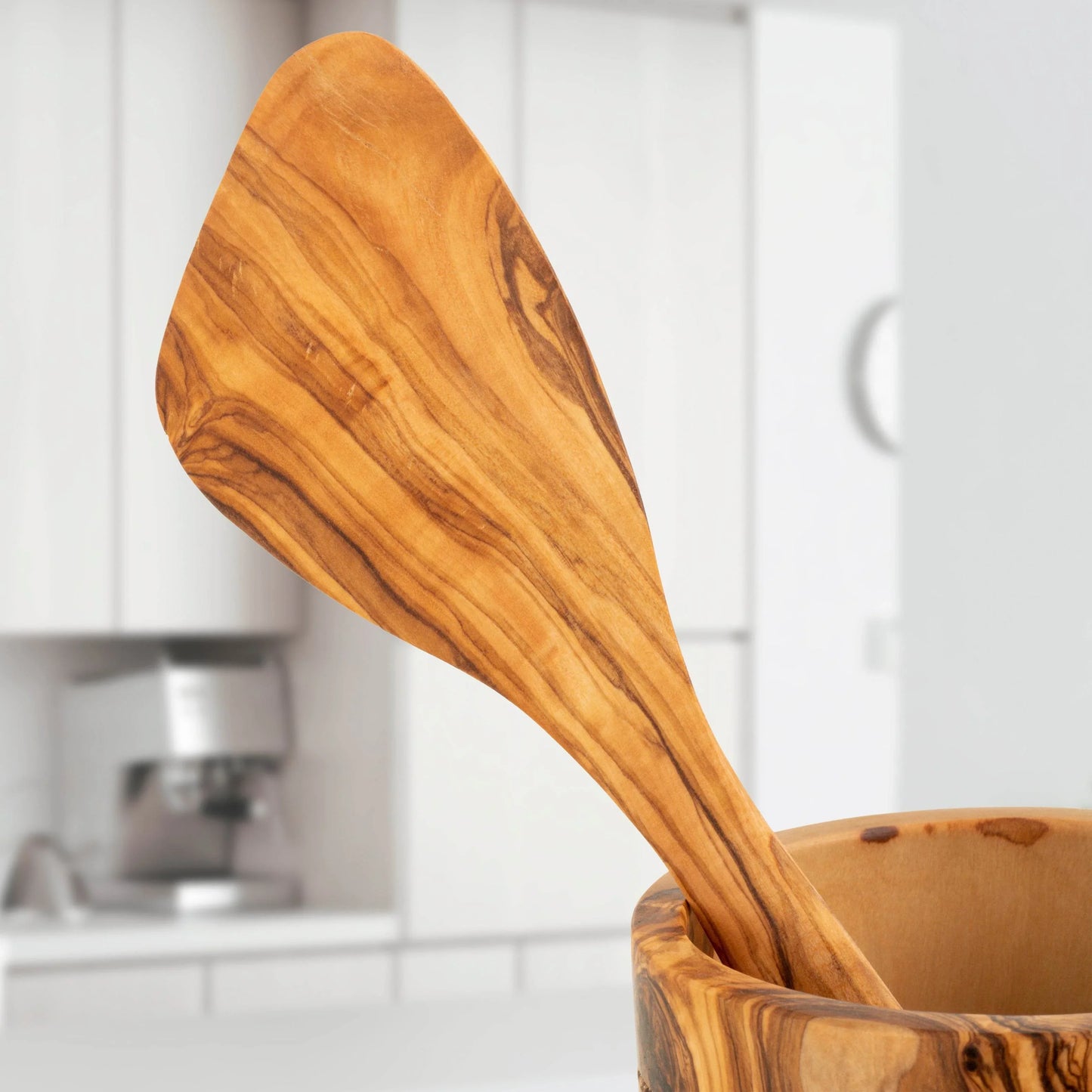 Turquoise Lucy handmade olive wood kitchen utensils resting in a matching wooden bowl in a modern kitchen