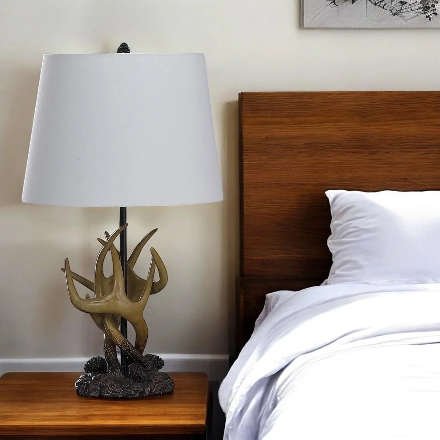 Natural antlers lamp with white shade on bedside table next to wooden bed with white bedding