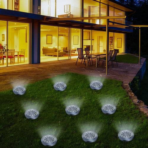 Pink Iolaus solar powered garden pathway lights illuminating an outdoor lawn by a modern glass house