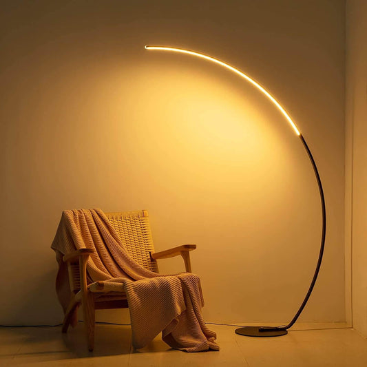Sangria Apricot modern curve floor lamp illuminating a cozy chair draped with a textured blanket